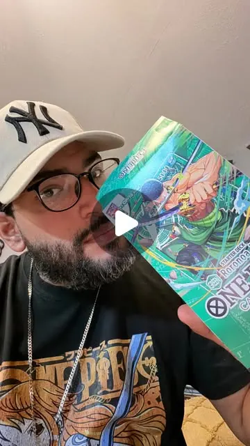Nino in a Yankees cap taking a selfie while holding up a One Piece booster pack